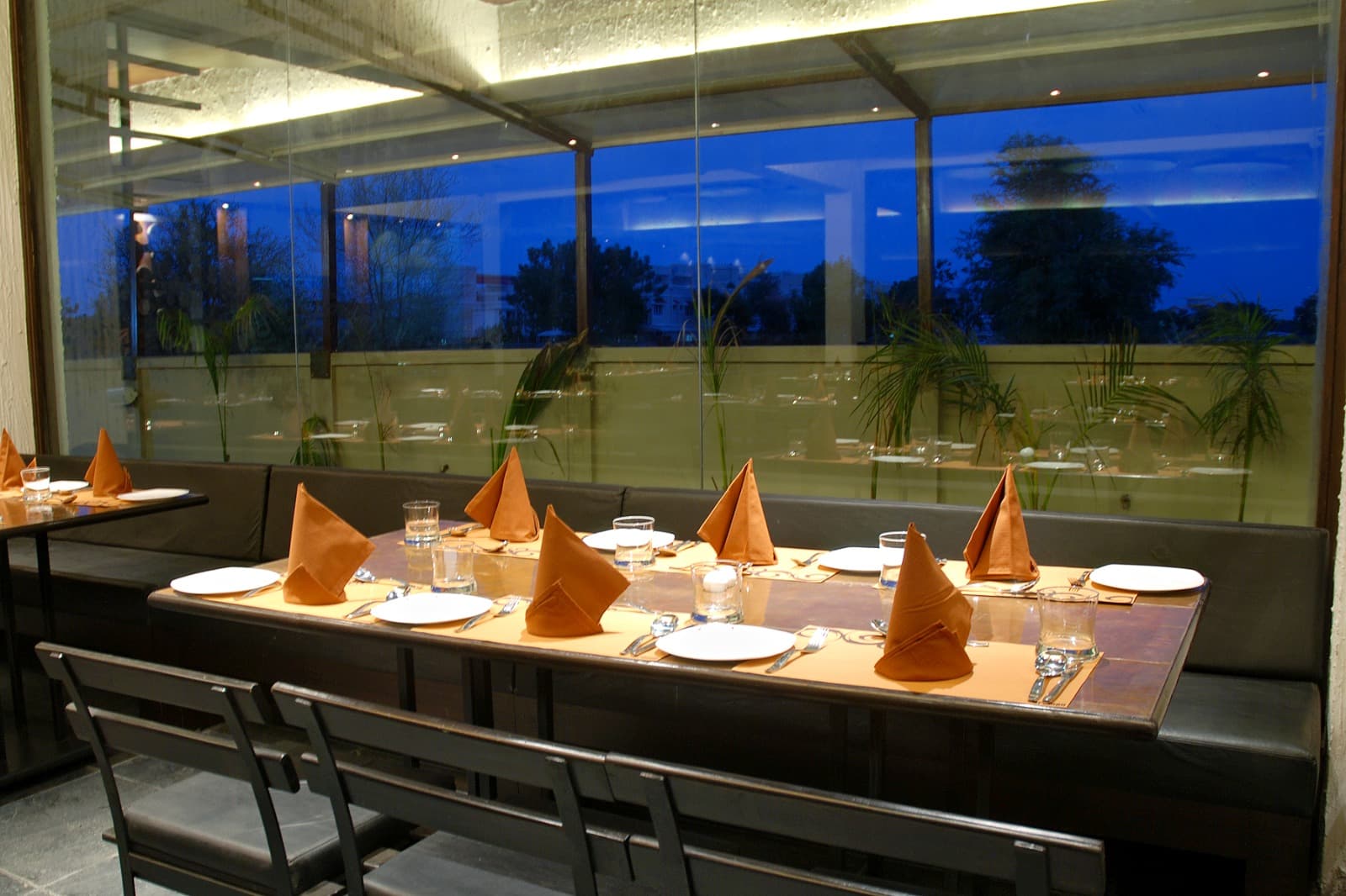 The Cooking Culture dining table set beside the glass wall at dusk