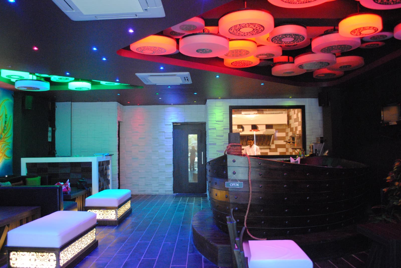 Karma lounge lit in neon blue and pink, with glowing cube seating