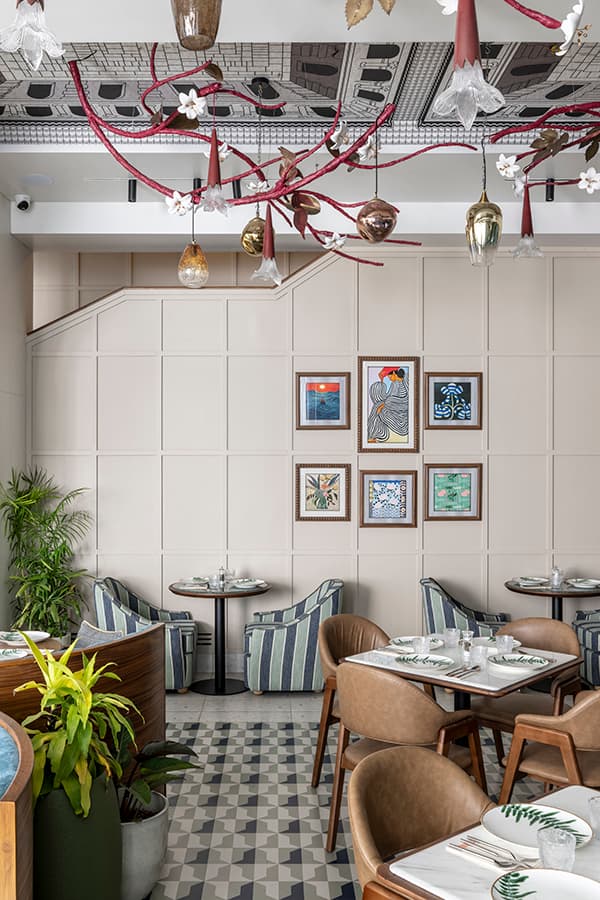 Beige panelled wall with framed prints above cane-back tables