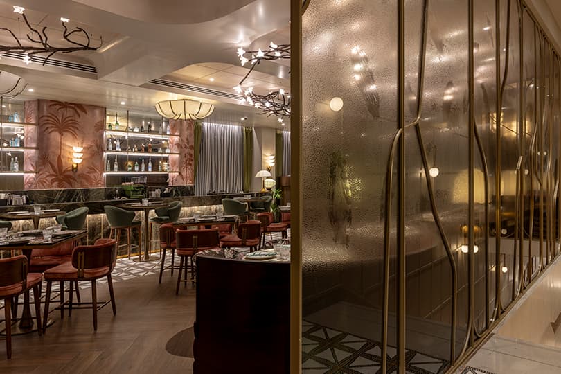 Lounge dining beyond a brass-framed glass partition