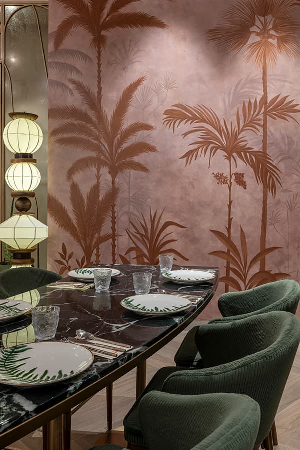 Palm-motif mural wall behind a set table