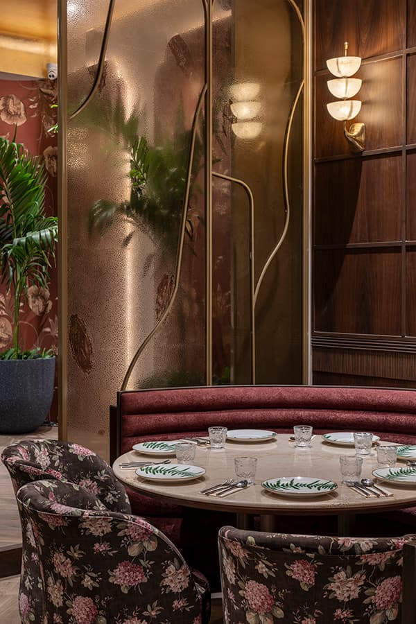Round table with floral armchairs and brass wall lights