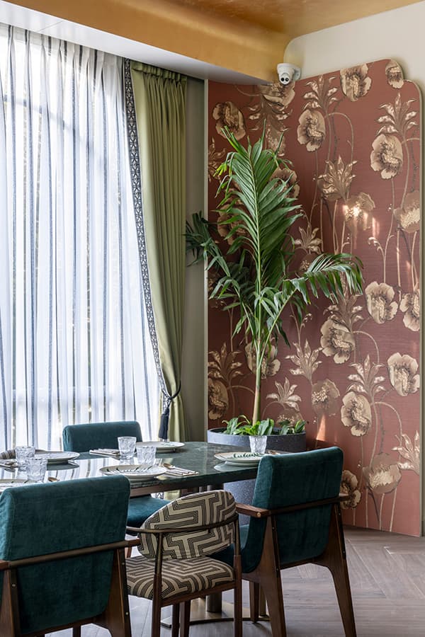 Table by the window with sheer curtains and a floral wall covering