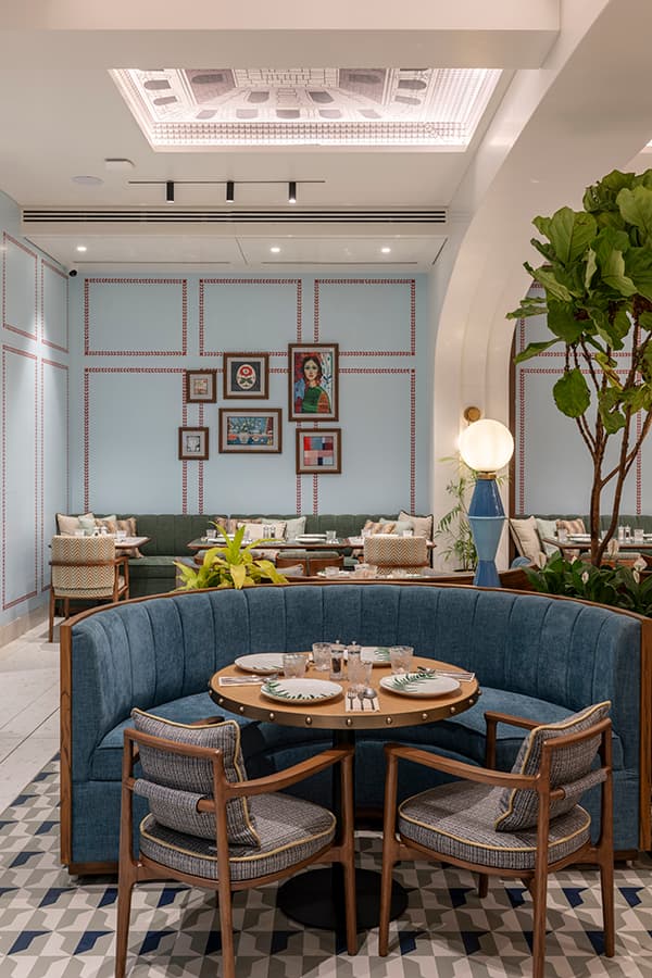 Blue booth and round table beneath the framed gallery wall