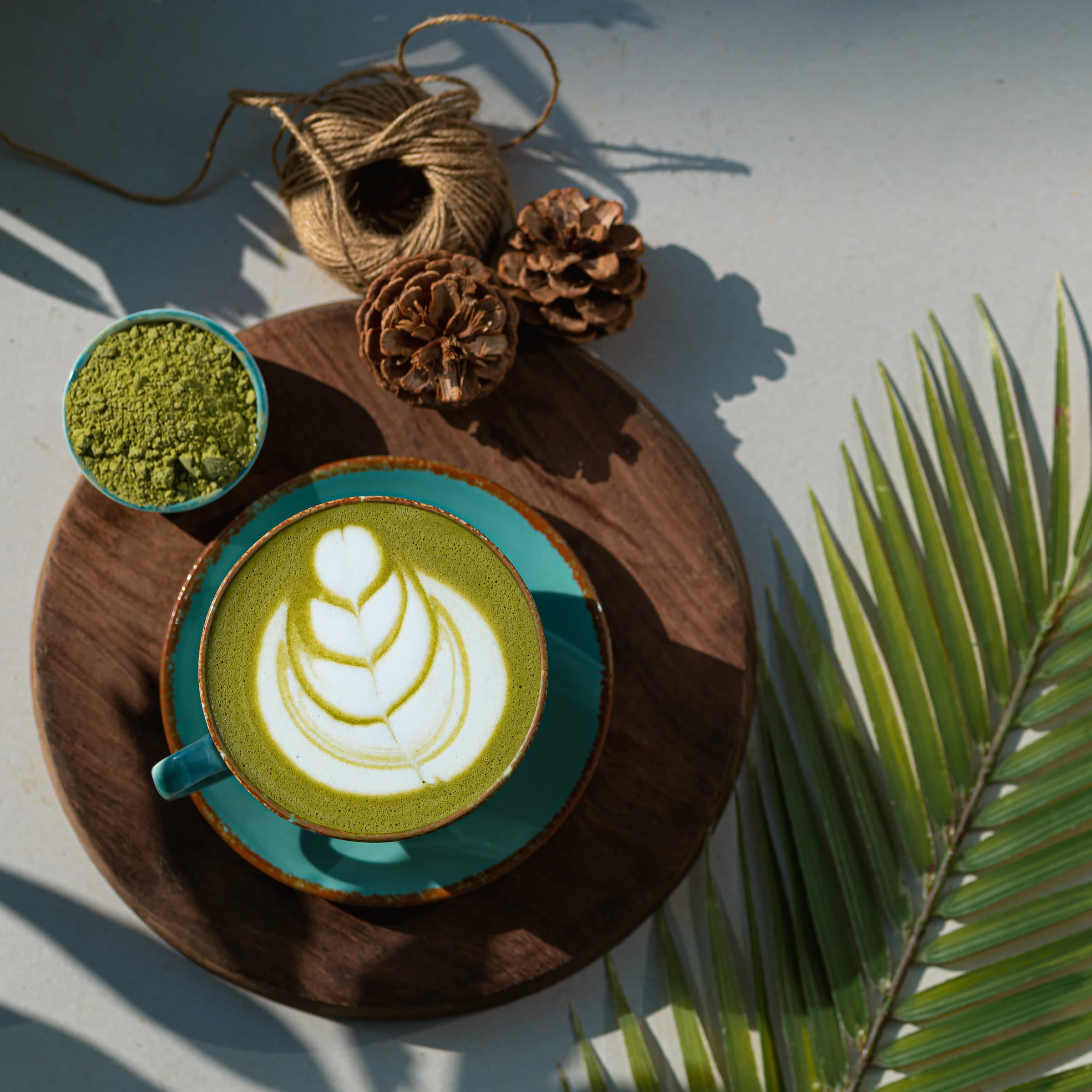 Hot matcha latte with poured art, on a wooden board