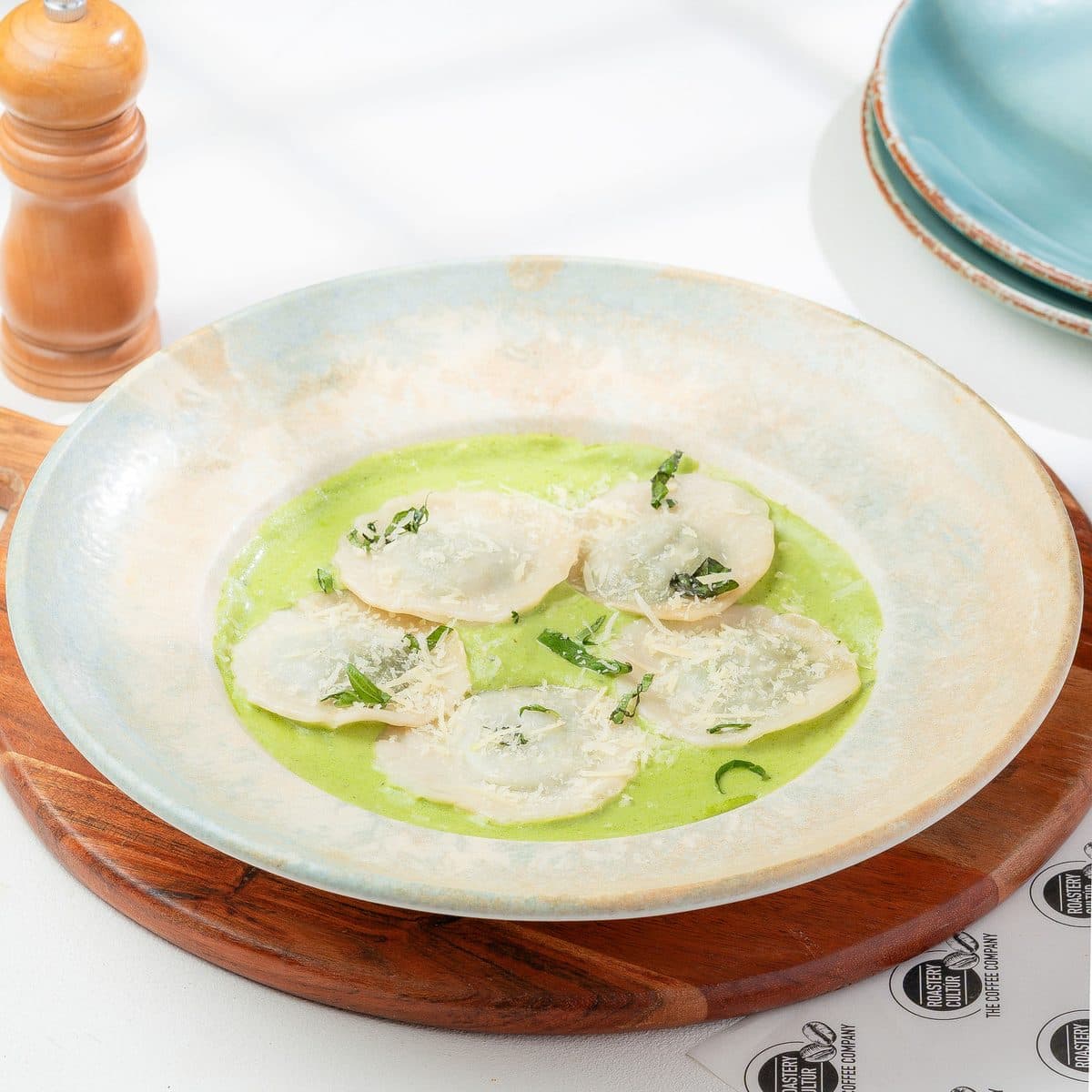 Ravioli in a herb sauce, served on a wooden board