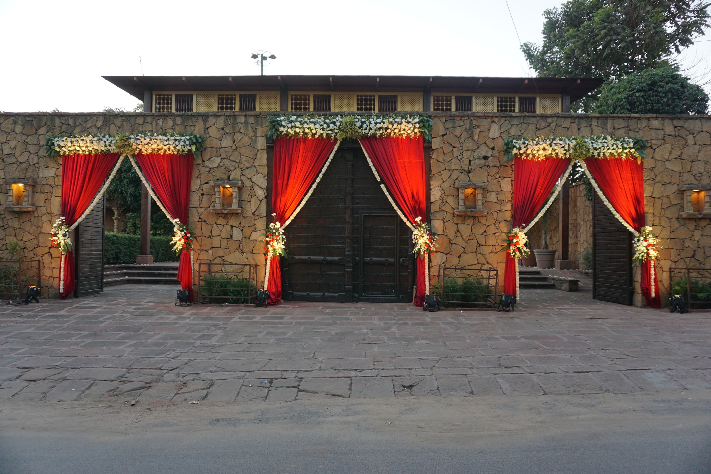 Stone gateway dressed with red curtains and marigold garlands