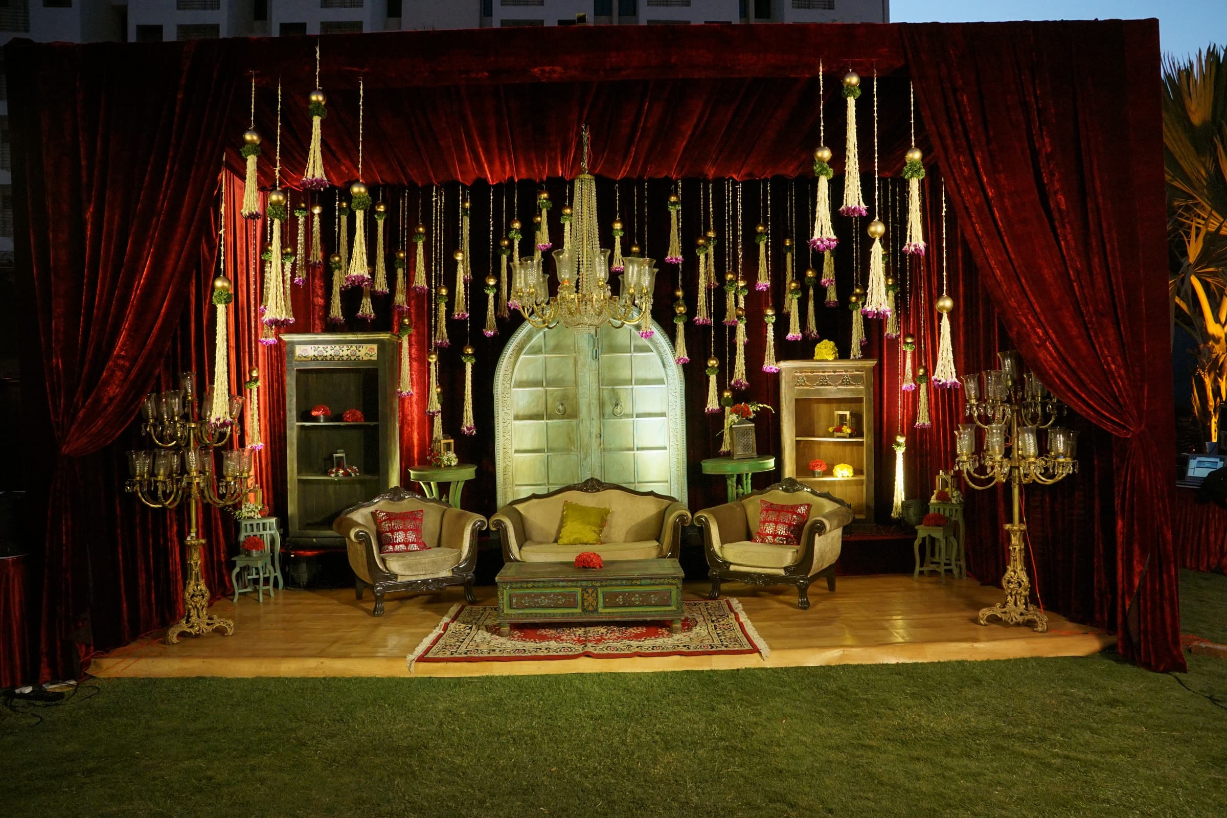 Throne-style stage with hanging lanterns and red drapes on the lawn
