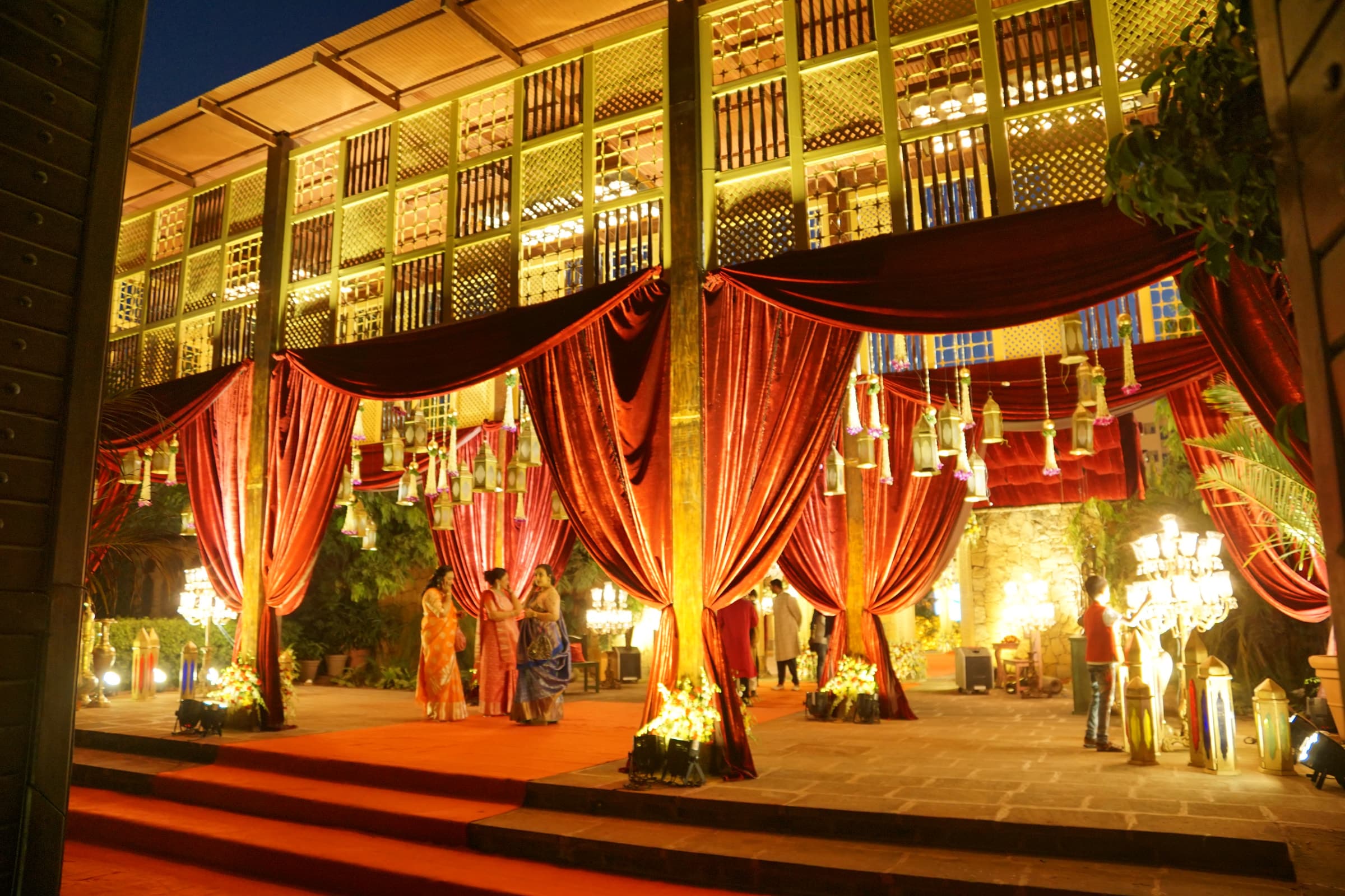 Stage under red drapes and lattice screens, lit for an evening celebration