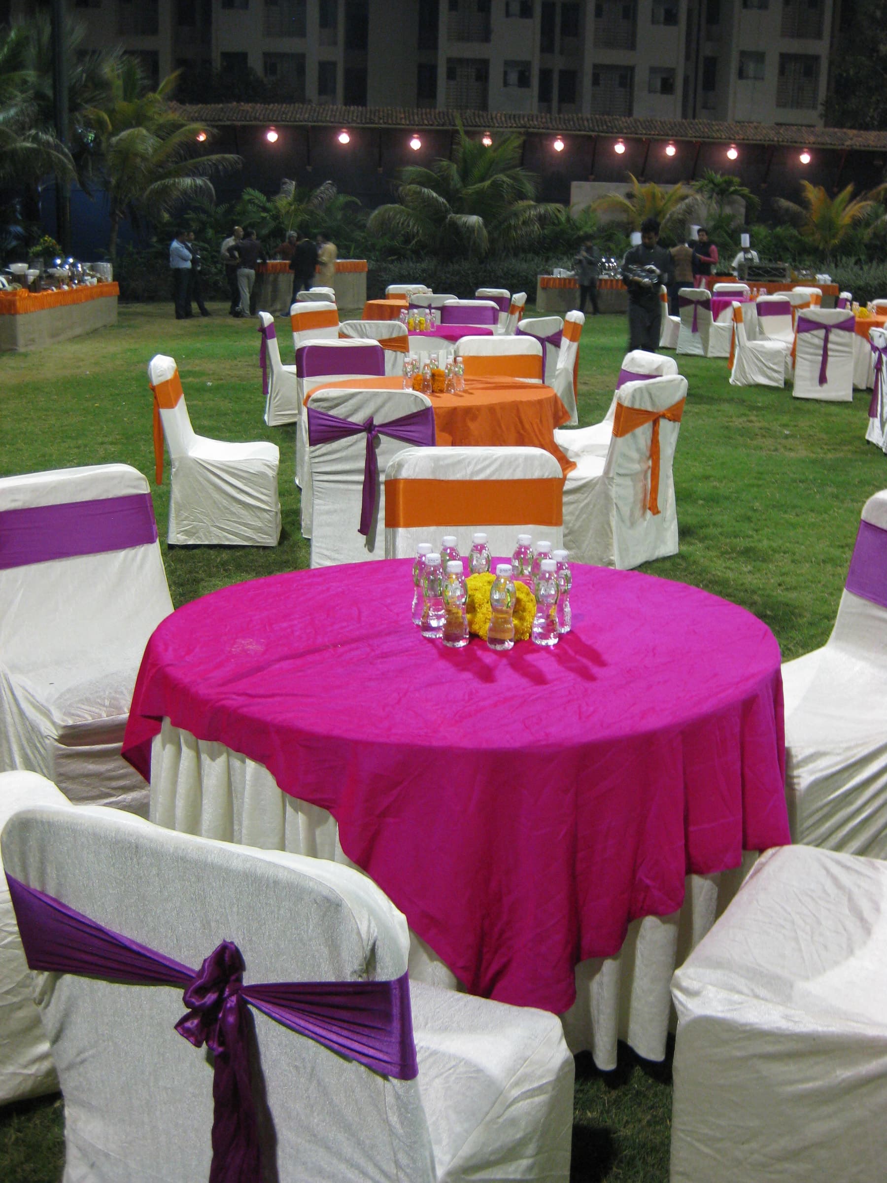 Magenta-linen round table with purple-sashed chairs on the lawn