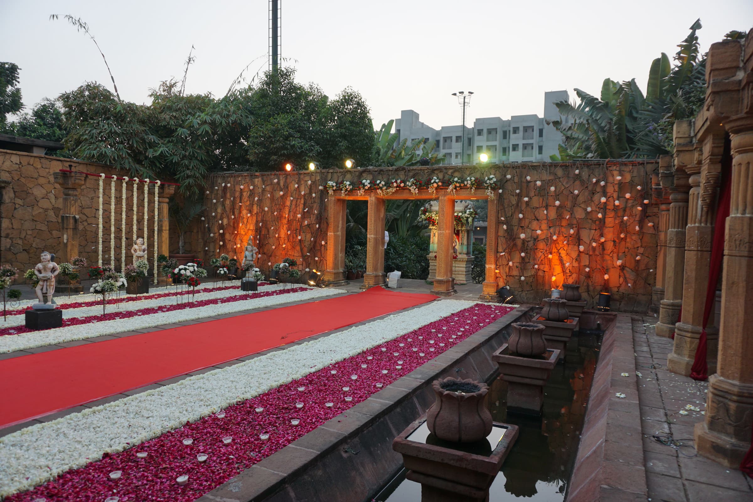Red carpet aisle strewn with petals leading to a heritage pavilion