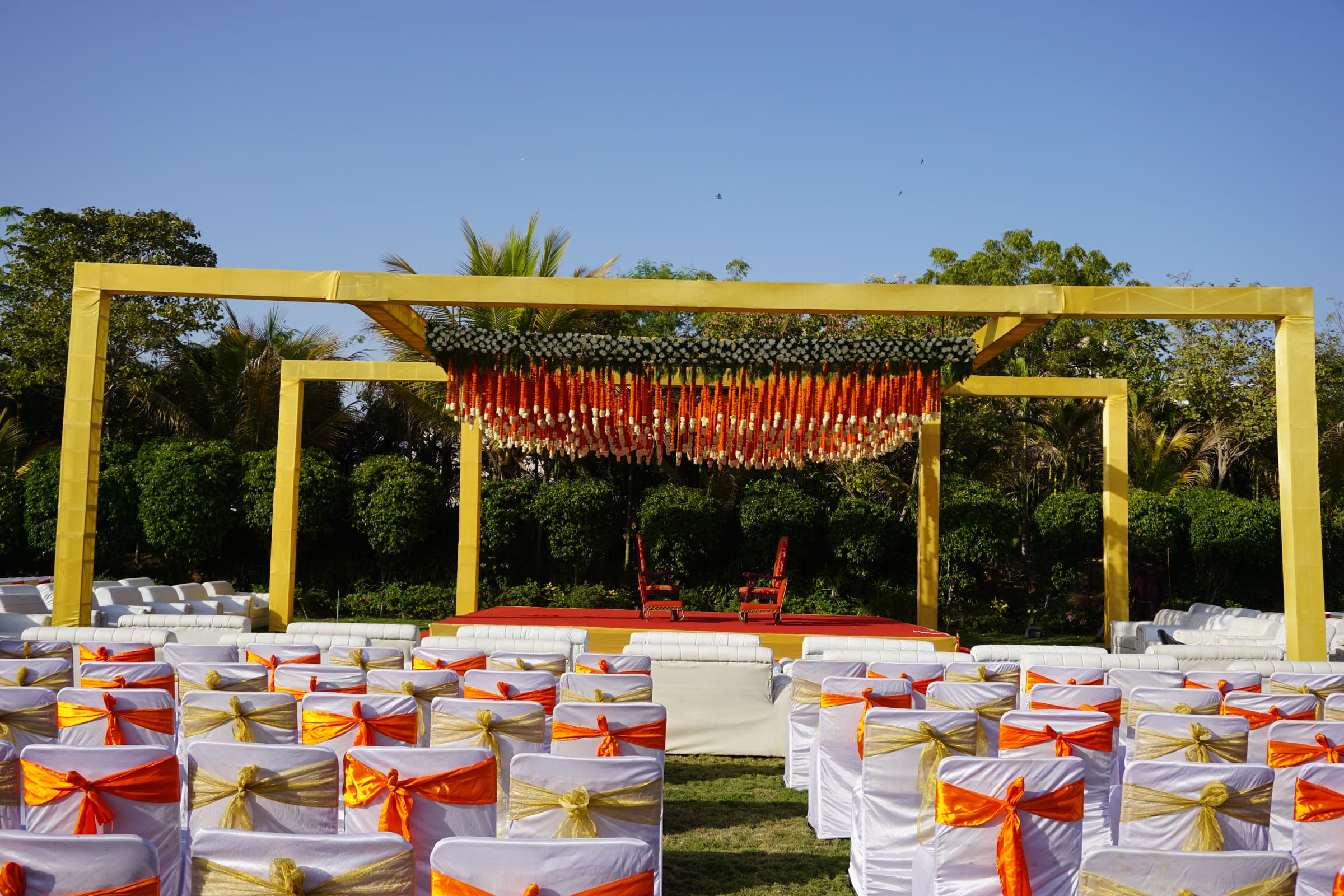 Yellow mandap framed in marigold over garden seating