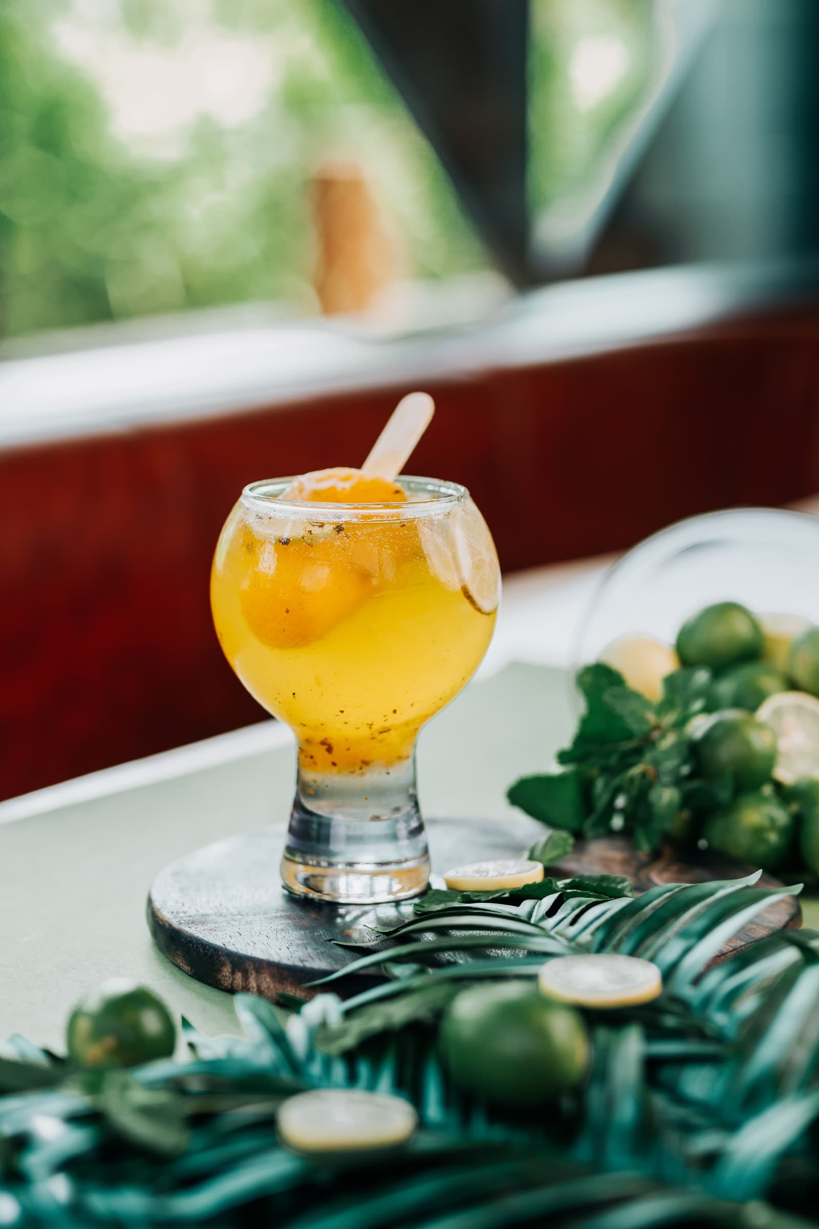 Golden citrus drink with lime garnish on a palm-leaf setting