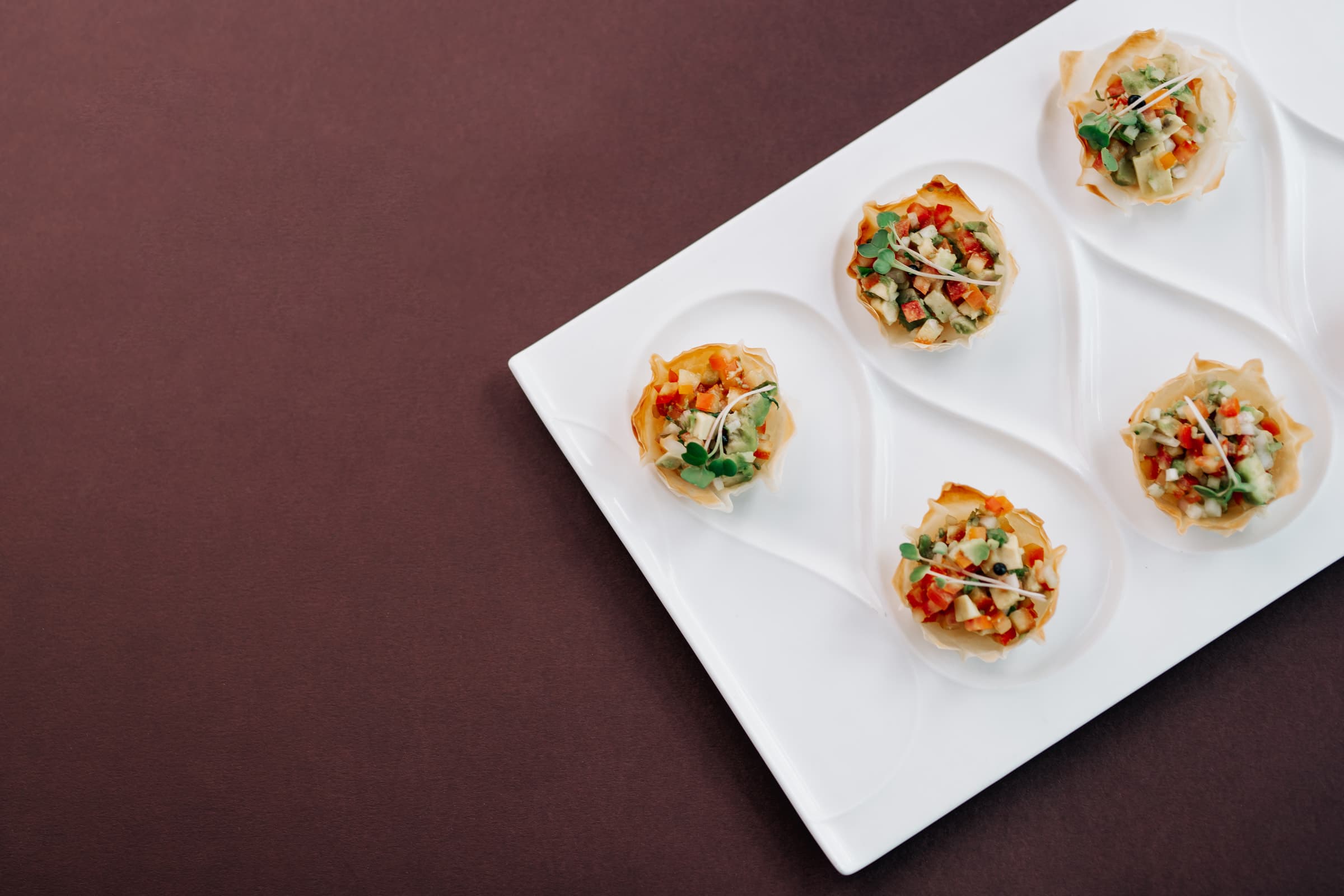 Bite-sized cups with colourful toppings on a white plate