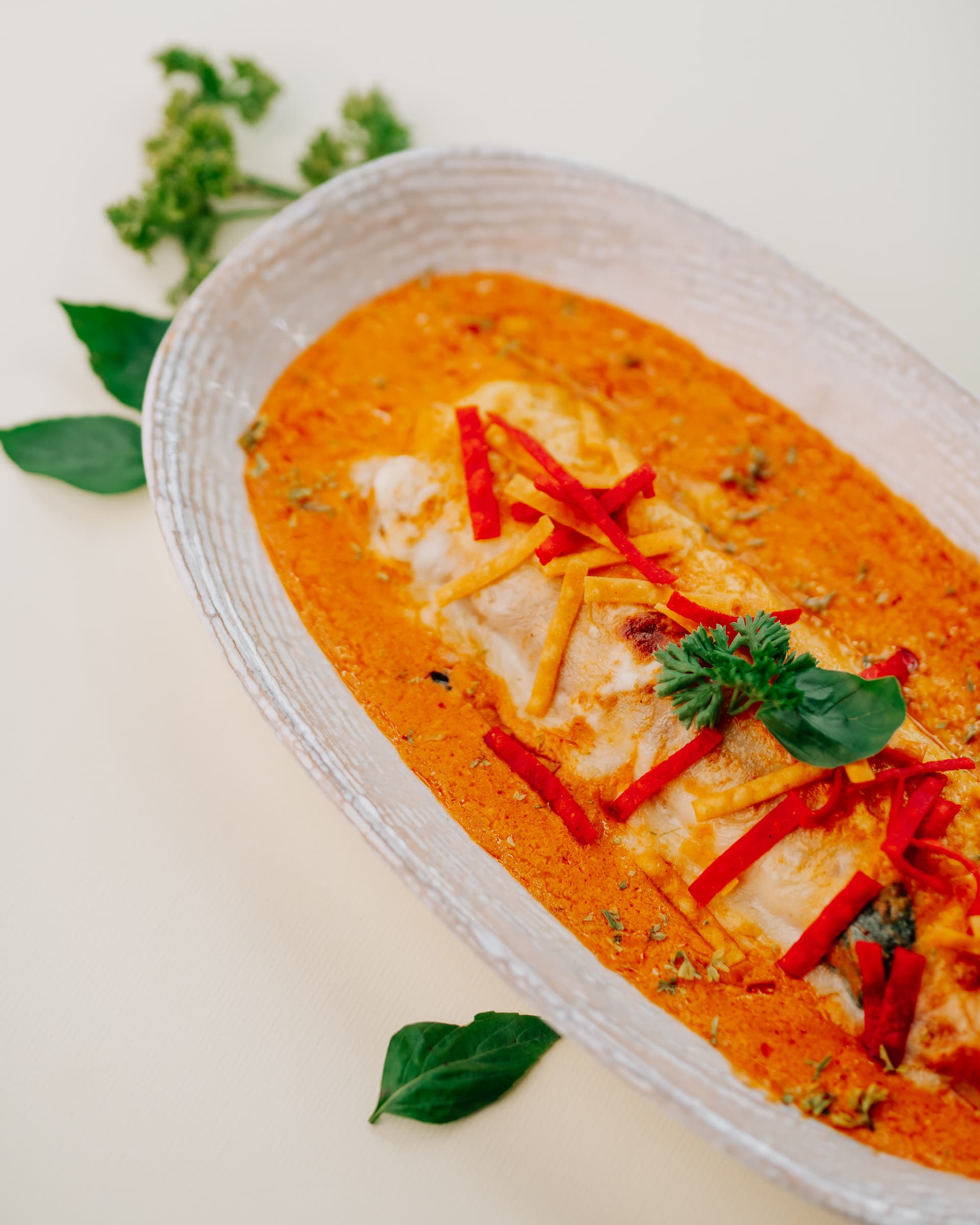 Creamy orange curry topped with red pepper strips and basil
