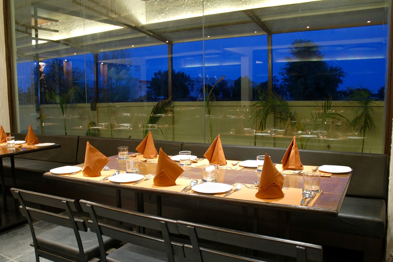 The Cooking Culture dining table set beside the glass wall at dusk