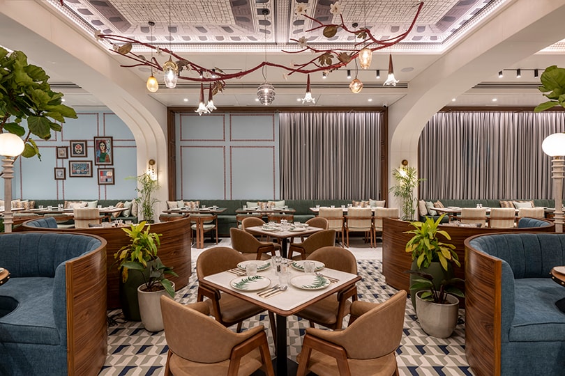 Dining hall under branch-like pendant lighting and a patterned ceiling