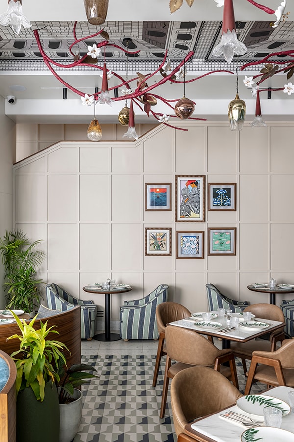 Beige panelled wall with framed prints above cane-back tables