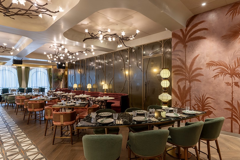Wide lounge with a palm mural and branch chandeliers