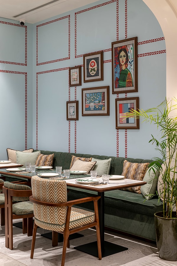 Sky-blue dining hall with framed artwork and green banquette seating