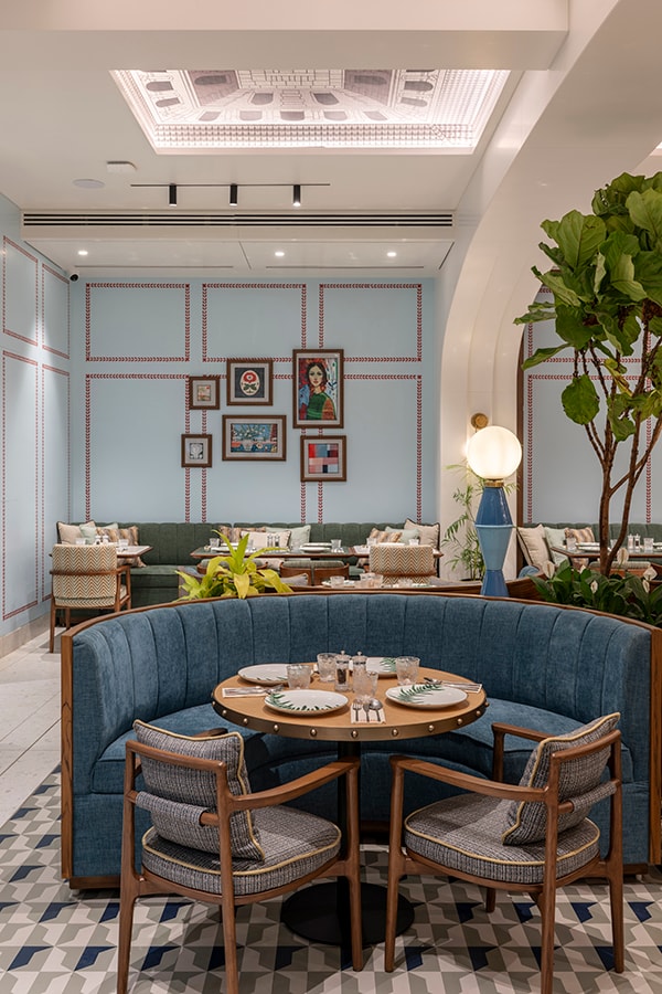 Blue booth and round table beneath the framed gallery wall