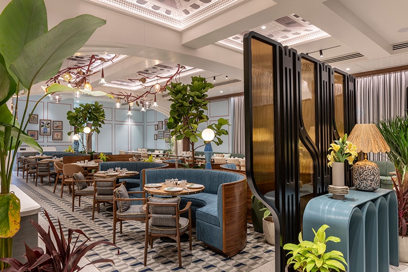 Brass screen partition dividing the dining hall, with layered planting