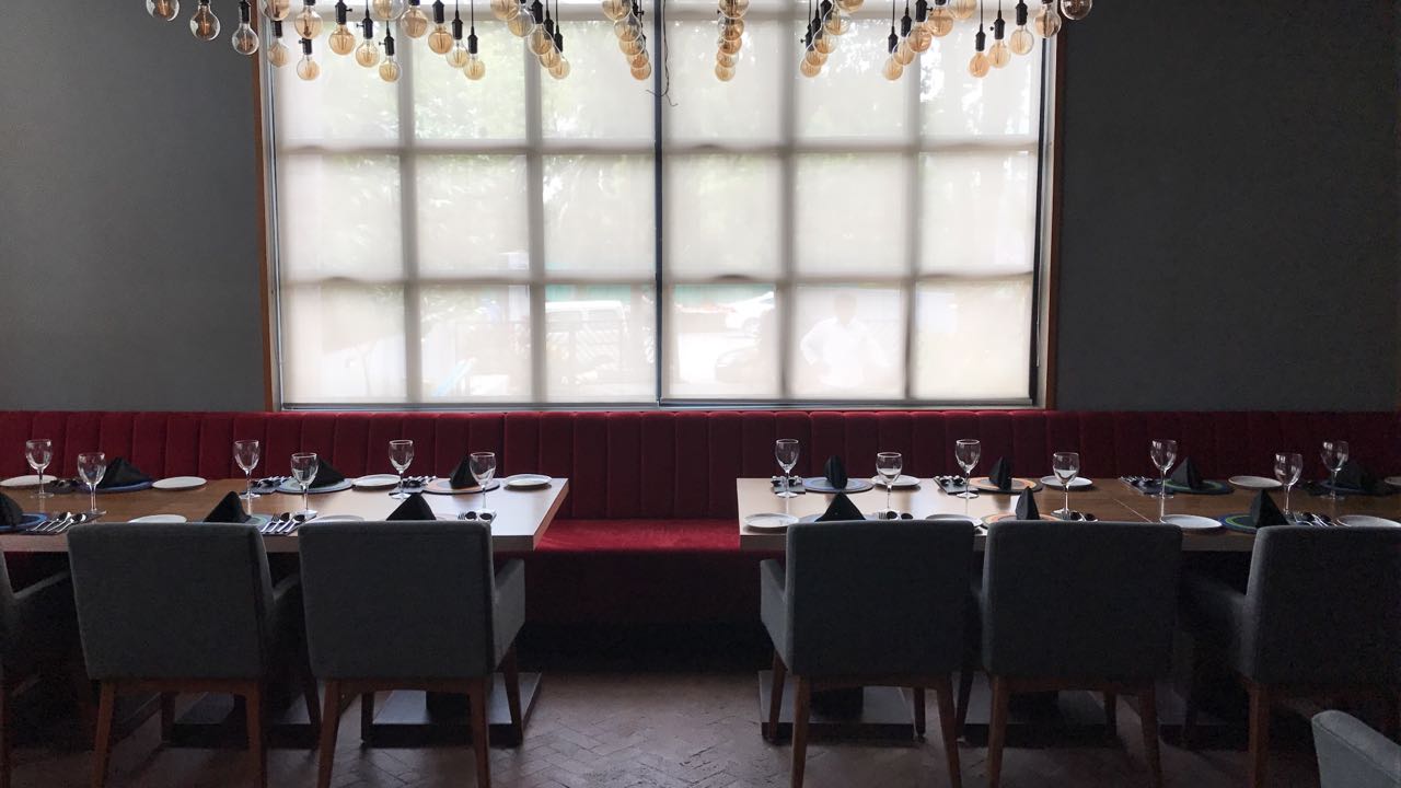 Backlit window wall above the red banquette seating