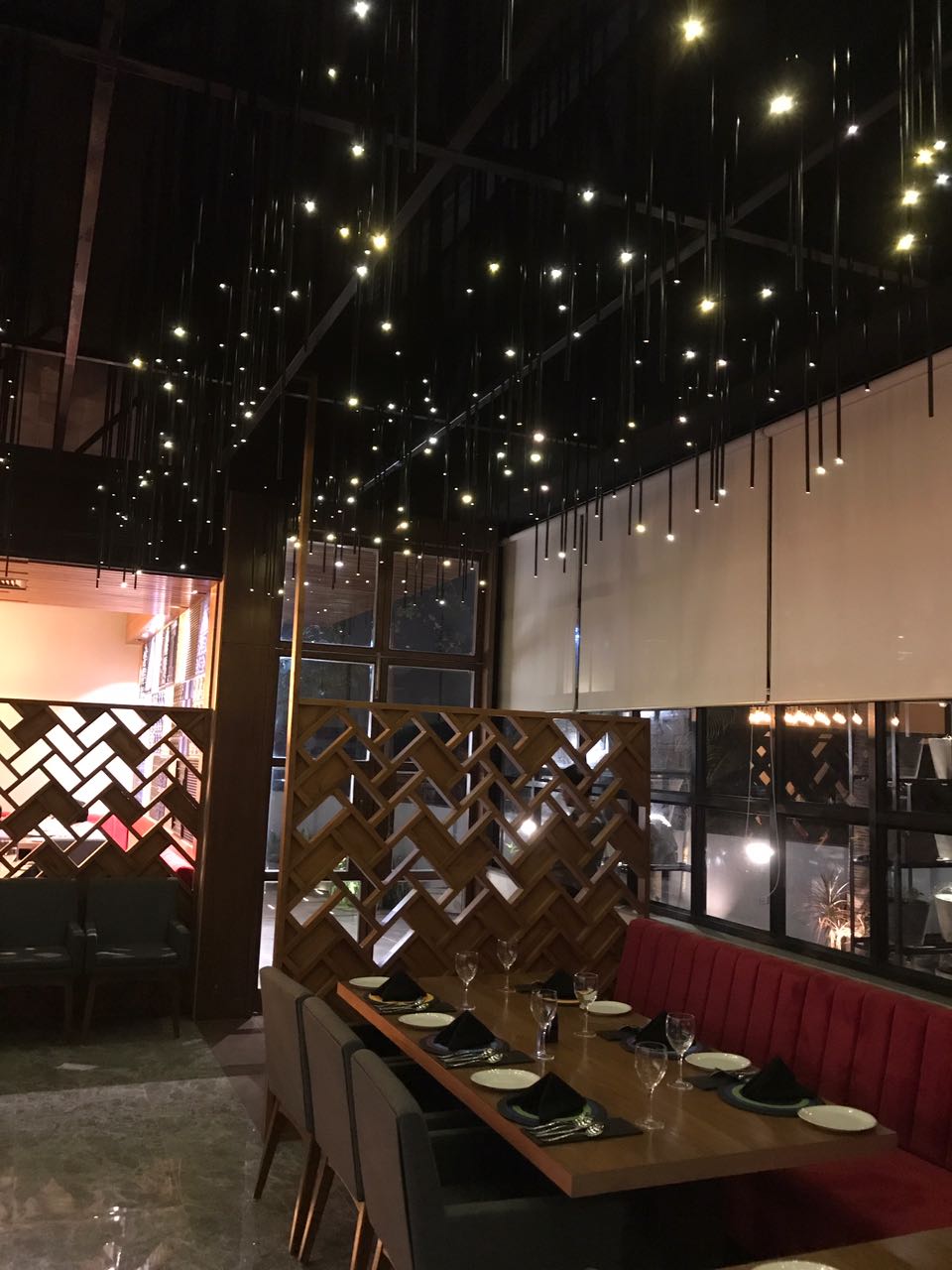 Long banquette table set beneath a canopy of string lights
