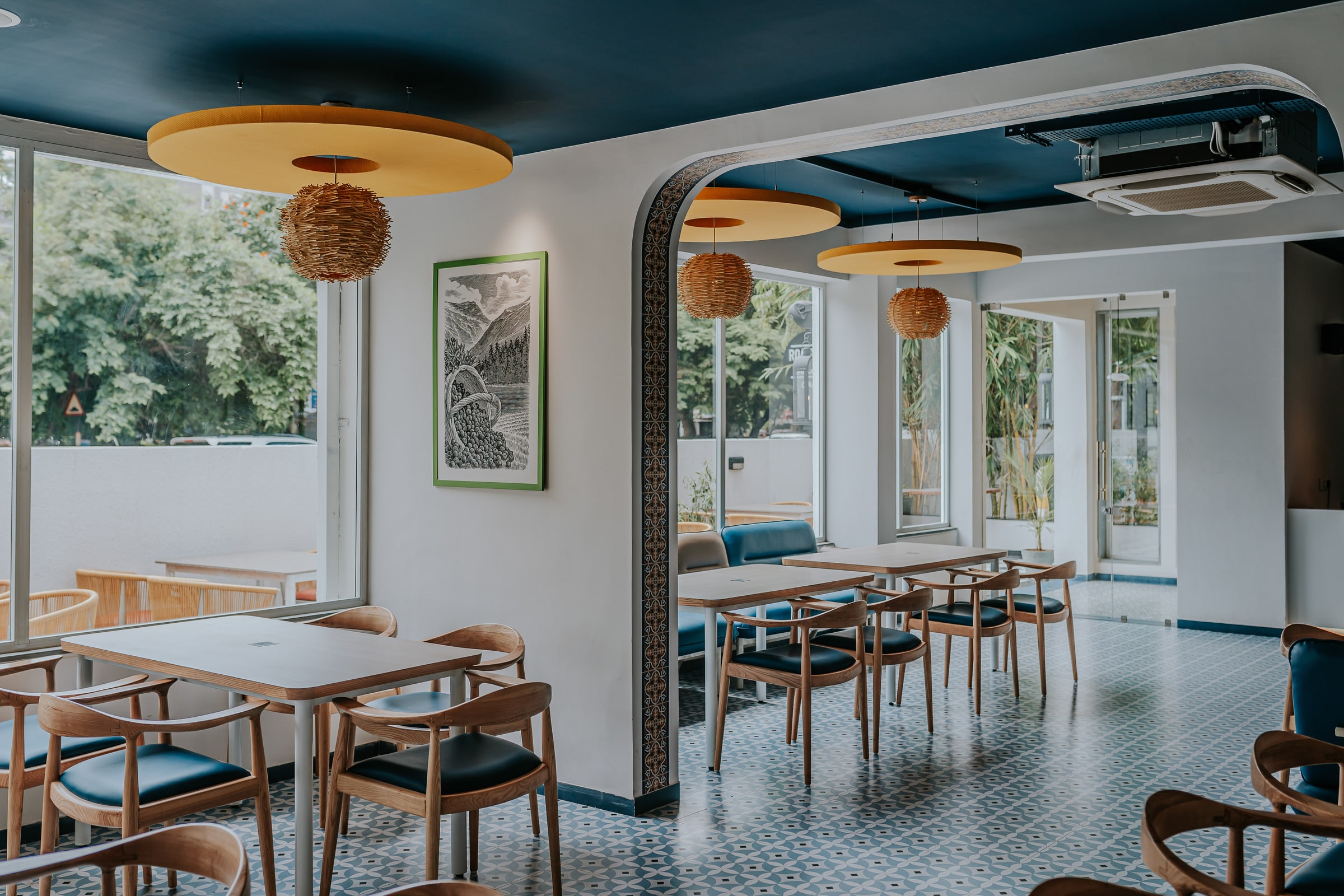 Roastery Cultúr dining room with garden-facing windows and woven pendant lights