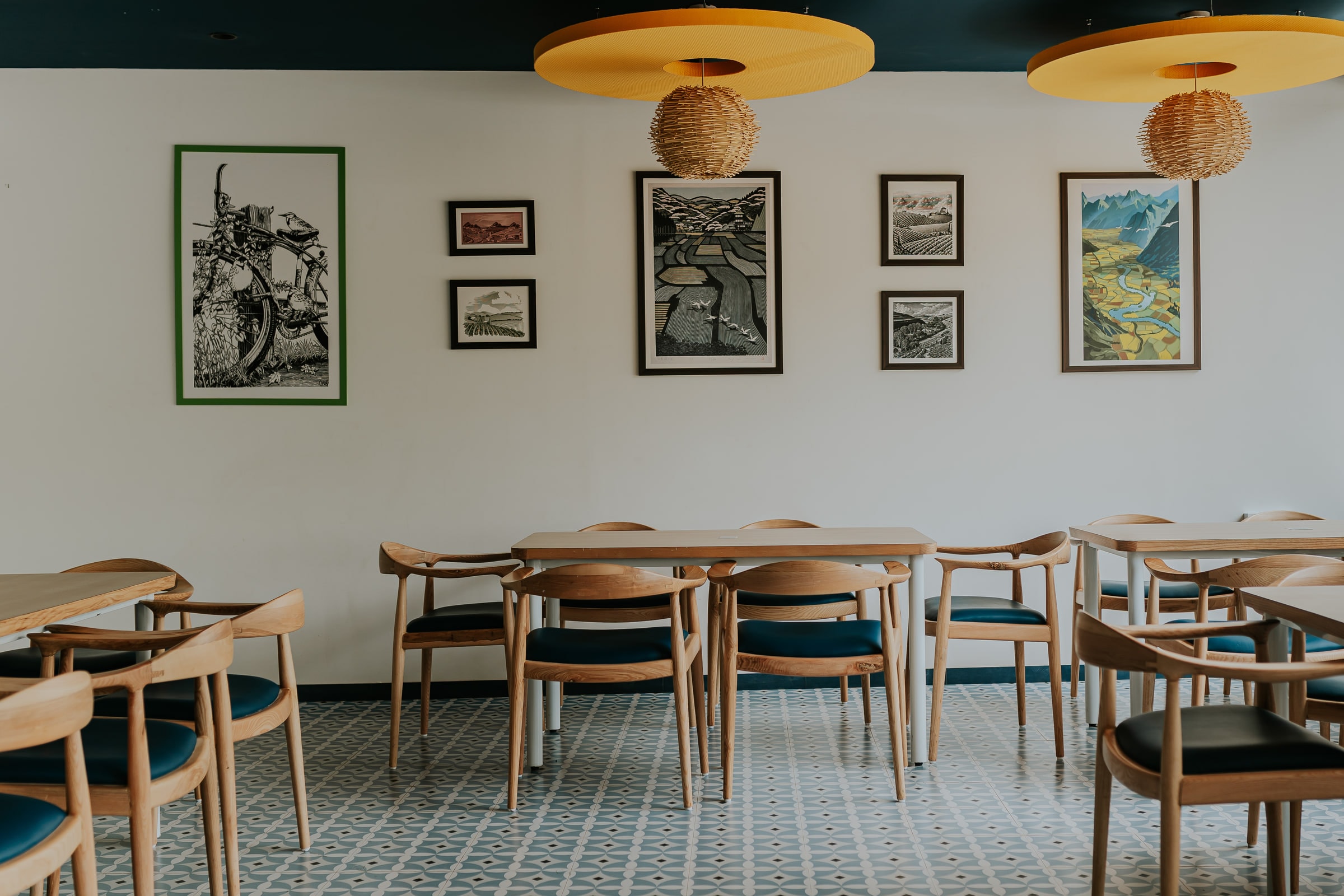 Framed prints above cane chairs and patterned tile flooring