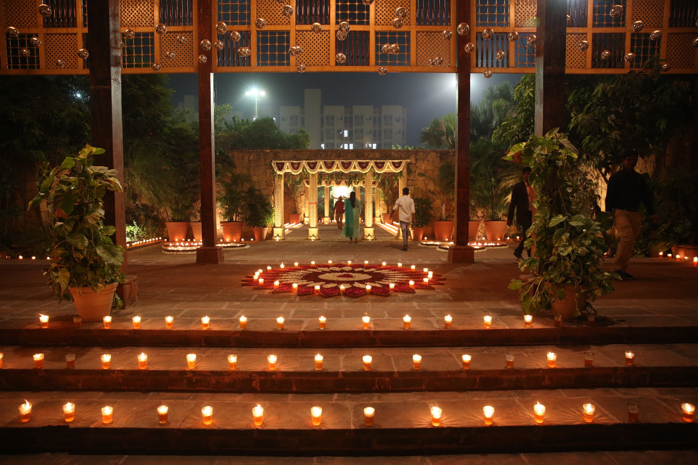 Candlelit steps and courtyard stage with a floral rangoli at dusk
