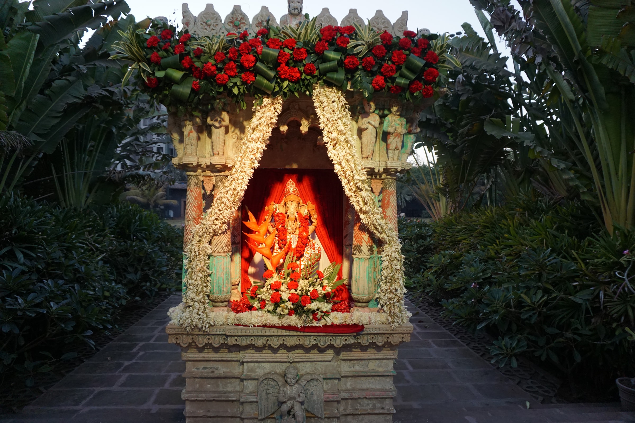 Floral-canopied shrine with red roses in the garden
