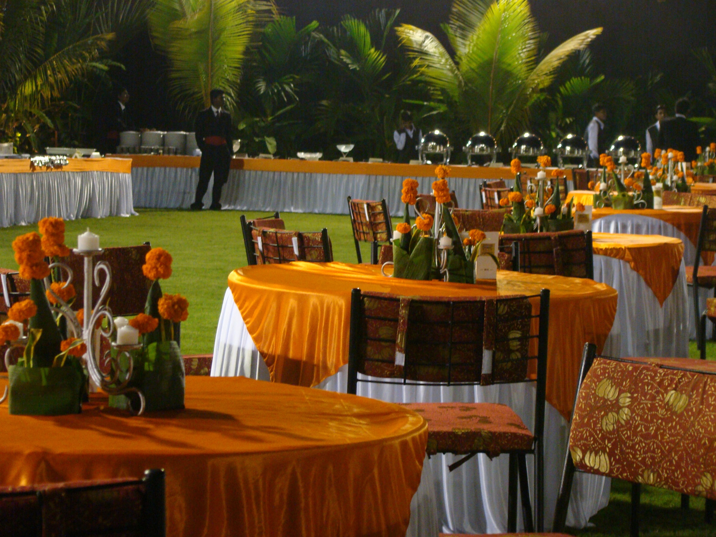 Lawn banquet tables set in orange and gold linen