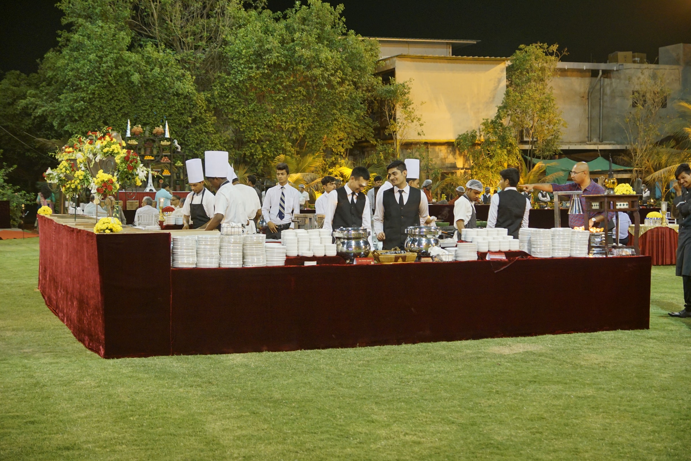 Live-counter buffet on the lawn with staff in uniform