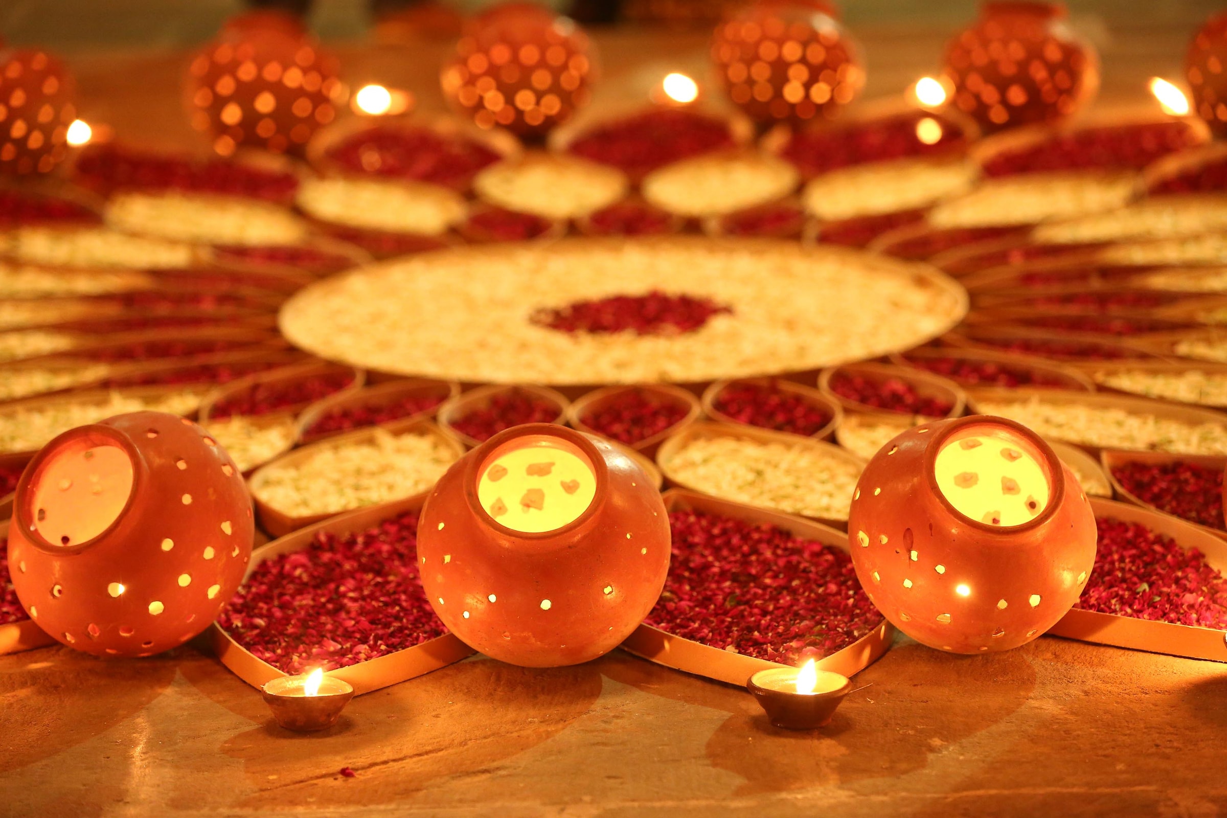 Rangoli of marigold petals and lit clay lamps