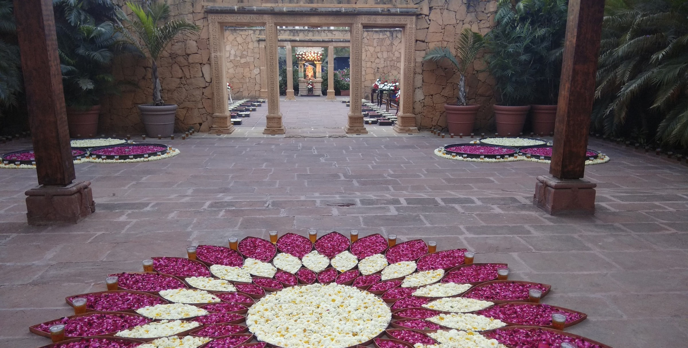 Floral rangoli in the stone courtyard at the entrance