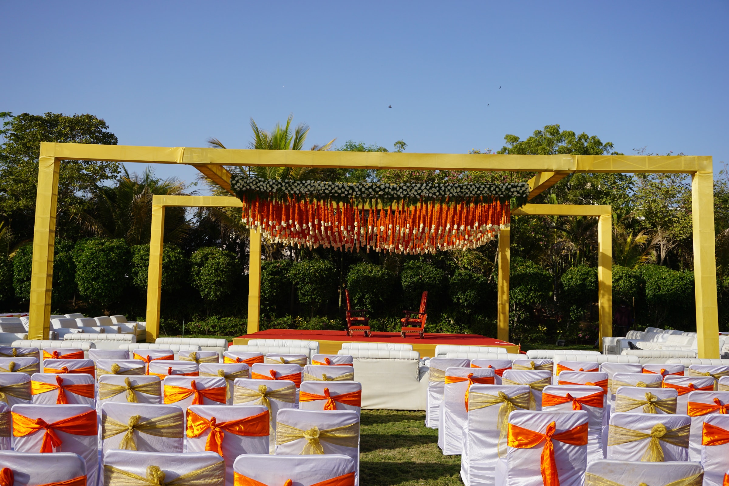 Yellow mandap framed in marigold over garden seating