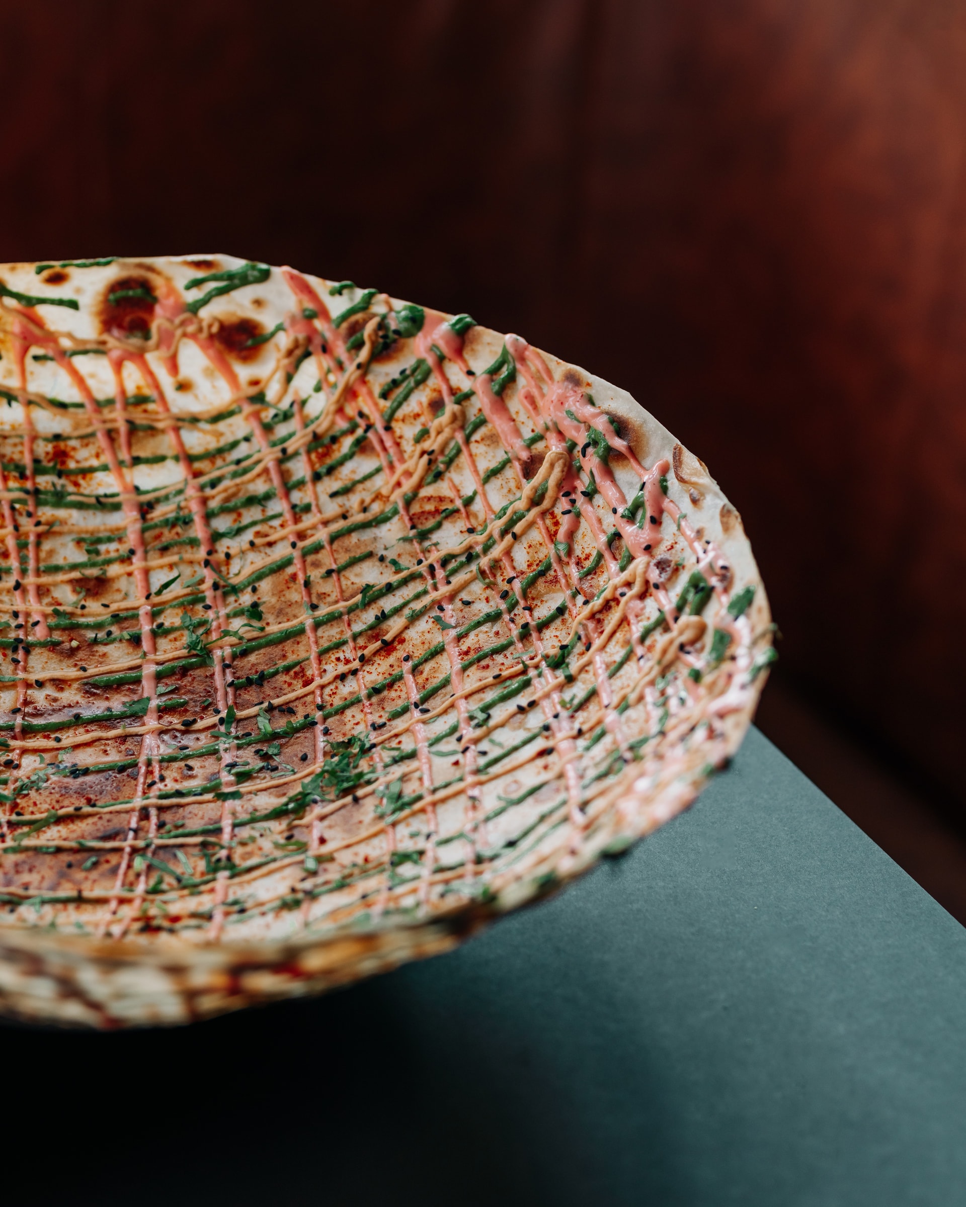 Woven crisp plate with a spiced drizzle on a dark table