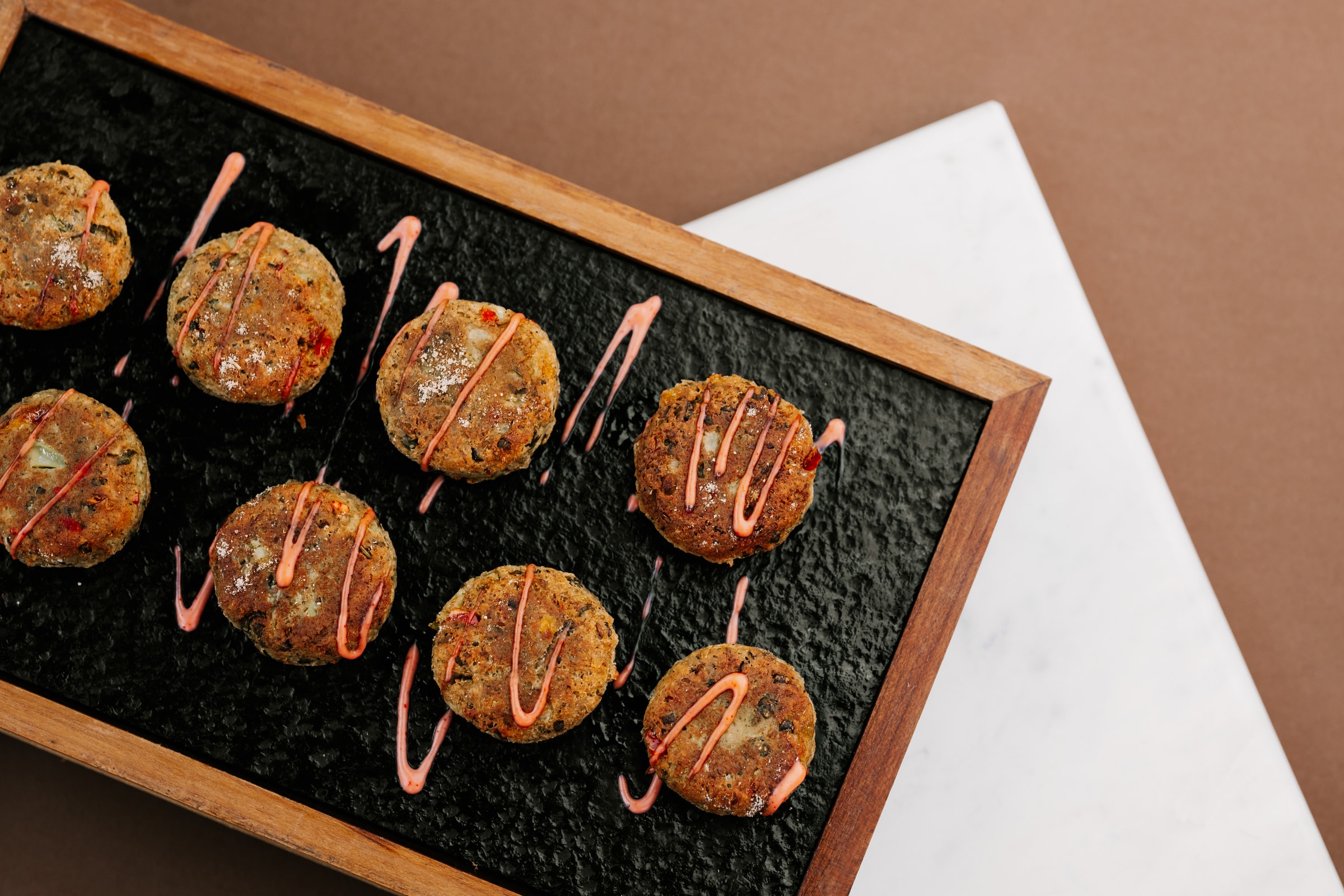 Round patties with a drizzle on a black slate tray