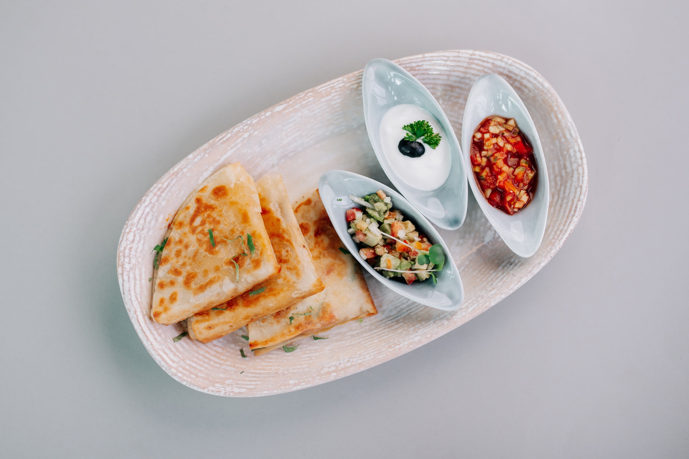 Grilled flatbread with three dips on an oval plate