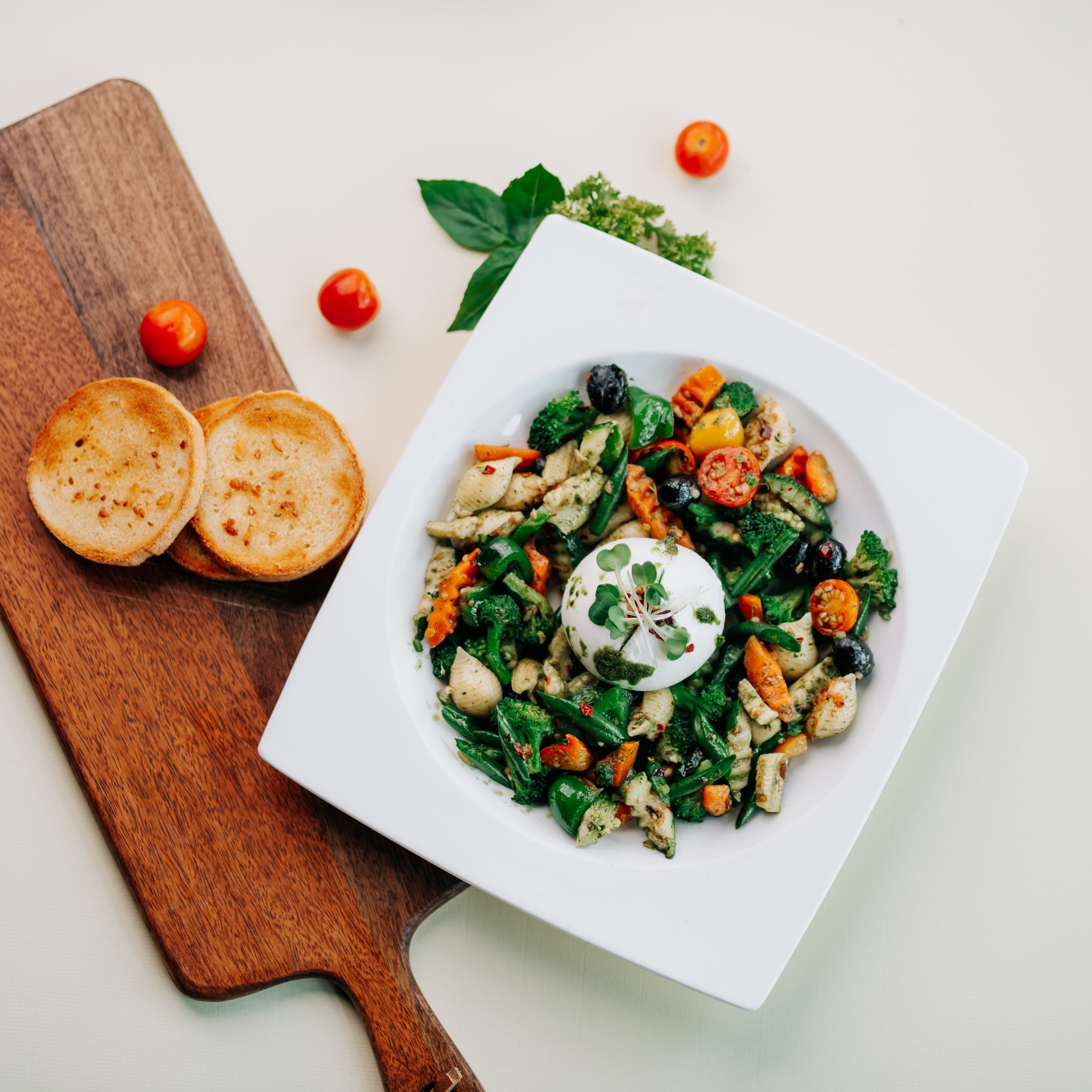 Salad with burrata beside garlic toast on a wooden board