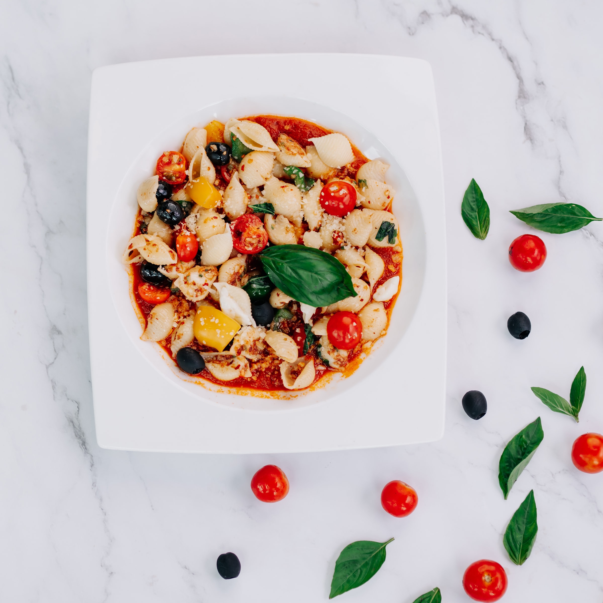 Pasta with tomatoes and basil on a marble surface